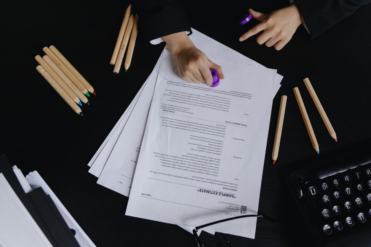 Crafting Captivating Headlines: Your awesome post title goes here Hands working with documents and colored pencils on a black desk view.